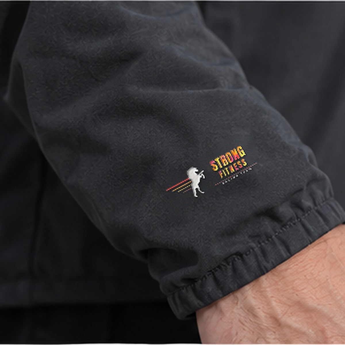 Detalle del logo Racing Team en la chaqueta softshell de Strong Fitness