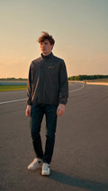 Chico con la chaqueta softshell Racing Team de Strong Fitness caminando por un circuito al atardecer
